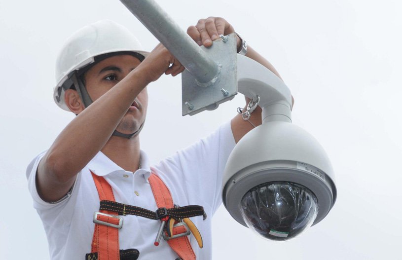 tecnico com capacete instalando camera de seguranca